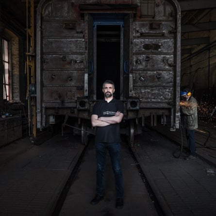 Yevhen Liashchenko, chief executive of Ukrainian Railways, standing in a rail shed with a man working on a wagon behind him.
