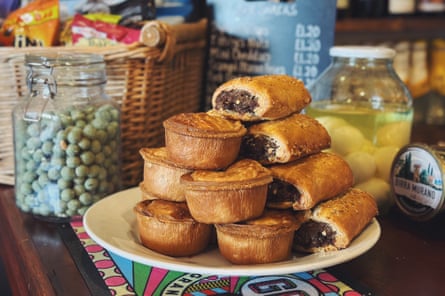 Homemade pork pies and sausage rolls piled on a plate on a pub bar