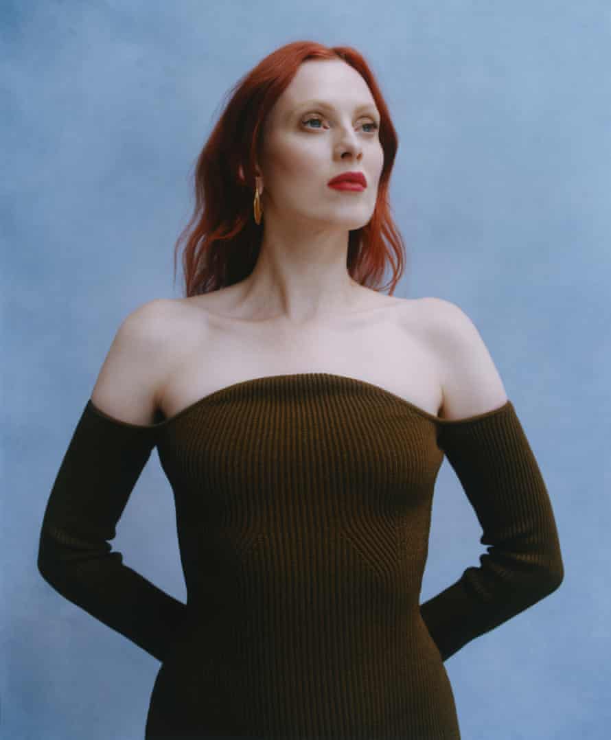 Model Karen Elson in brown shoulderless dress against blue background