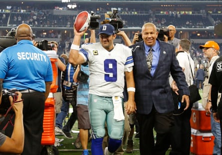 Tony Romo holds a football in the air after a Dallas Cowboys game.