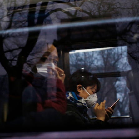 People wearing masks sit in a bus during heavy traffic amid thick smog in Beijing