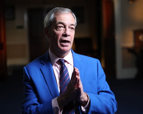 A grey-haired man in an electric blue jacket and blue and pink striped tie with his hands in the prayer position and his mouth open