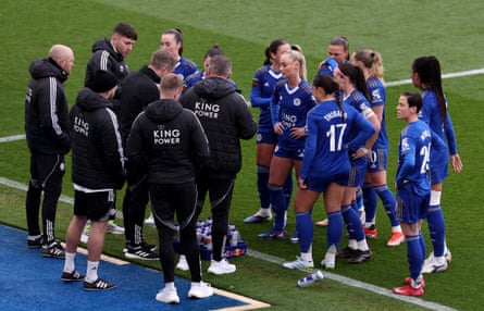 Leicester’s players and staff gather on the touchline during a break in play.