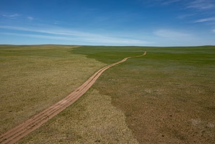 A faint scar from a recent fire crosses a rural road in Eastern Mongolia