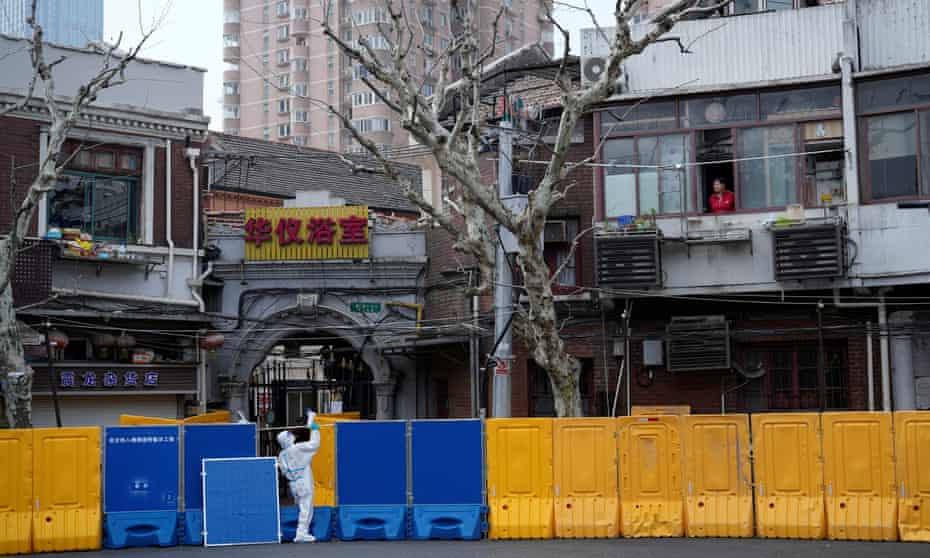 A worker calls through a megaphone for residents to go for testing inside the barriers of an area in Shanghai under lockdown.