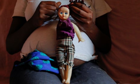 Jackline, 17, who is seven months pregnant, holds a doll