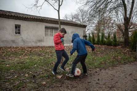 Dos niños juegan al fútbol al aire libre mientras usan mascarillas