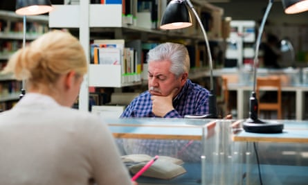 Older man studying among young college students in library