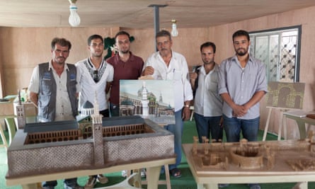 Artists in Zaatari refugee camp with their work, including a model of the Umayyad mosque in Damascus