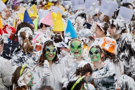 Three people in fancy dress with green face strand out among foam fight students