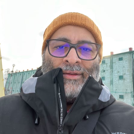 A bearded man in a knit cap, glasses and a parka.
