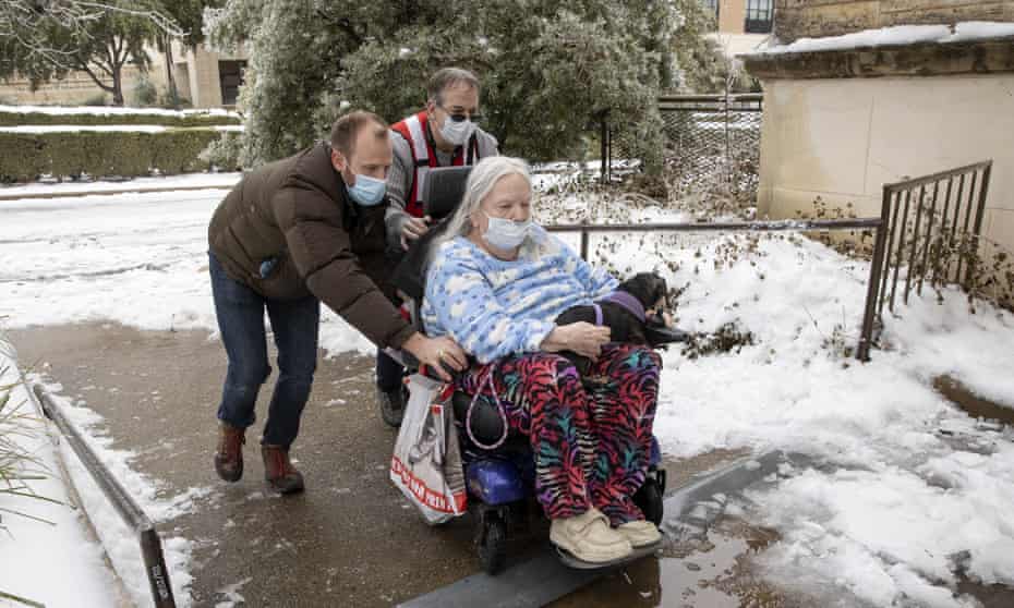 Dori Ann Upchurch is assisted by an Austin Disaster Relief Network volunteer, Cody Sandquist, left and a Red Cross volunteer to a heating station in Austin, Texas.