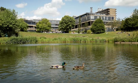 University of Bath exterior showing a large pond with ducks, a grassy verge and university buildings.