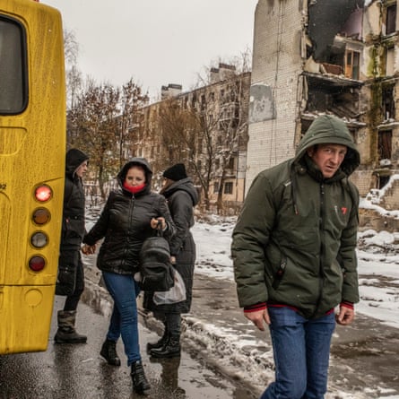 Residents of Borodianka get off a bus in a street heavily bombed by Russia