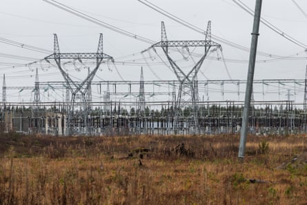 Tall electrical pylons and transmission towers stand over a substation near Oulujoki river, Finland.