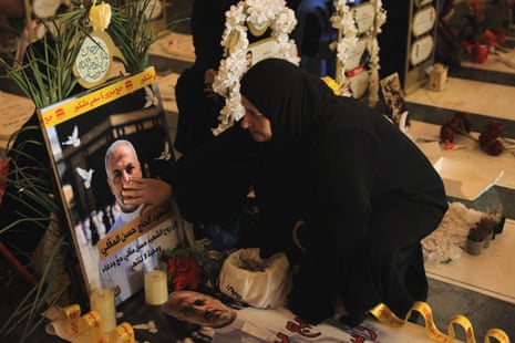 A woman touches a photo of a man on a gravestone.