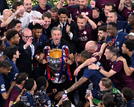Luis Enrique, the Paris Saint-Germain head coach, lifts the Champions League trophy surrounded by the club's players and staff after his team's 5-0 win over Inter Milan in the 2025 Champions League final at the Allianz Arena in Munich.