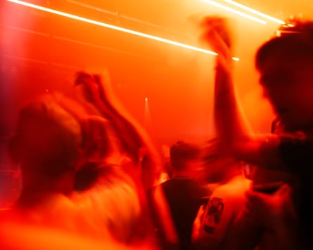 People dancing at a club with their hands in the air