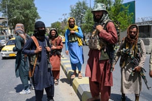 Taliban fighters stand guard along a street near Zanbaq Square in Kabul