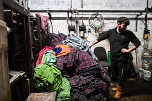 A worker stands next to a pile of different coloured and patterned fabric
