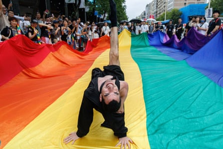 A participant dances on a large rainbow flag during the 2025 Taiwan Pride Parade in Taipei