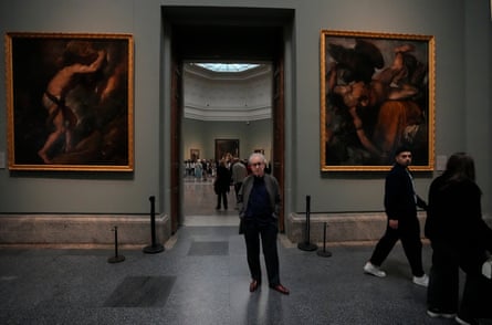 John Banville stands at the entrance to a room int he Prado flanked by two large paintings
