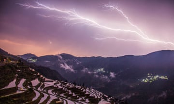 A bolt of lightning crosses the sky over the terraced fields
