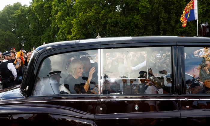 ملکه کامیلا هنگام خروج او و شاه چارلز از کاخ باکینگهام دست تکان می دهد.