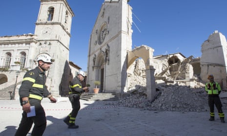 Firefighters walk past Norcia’s damaged town hall and basilica the day after the earthquake hit central Italy, on 31 October 2016. 