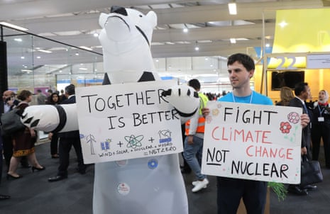 People hold banners next to an inflatable polar bear inside the International Congress Center.