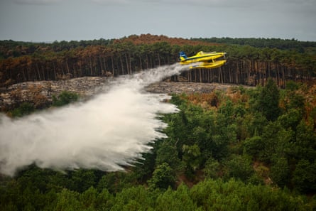 A firefighting plane drops water over a forest fire