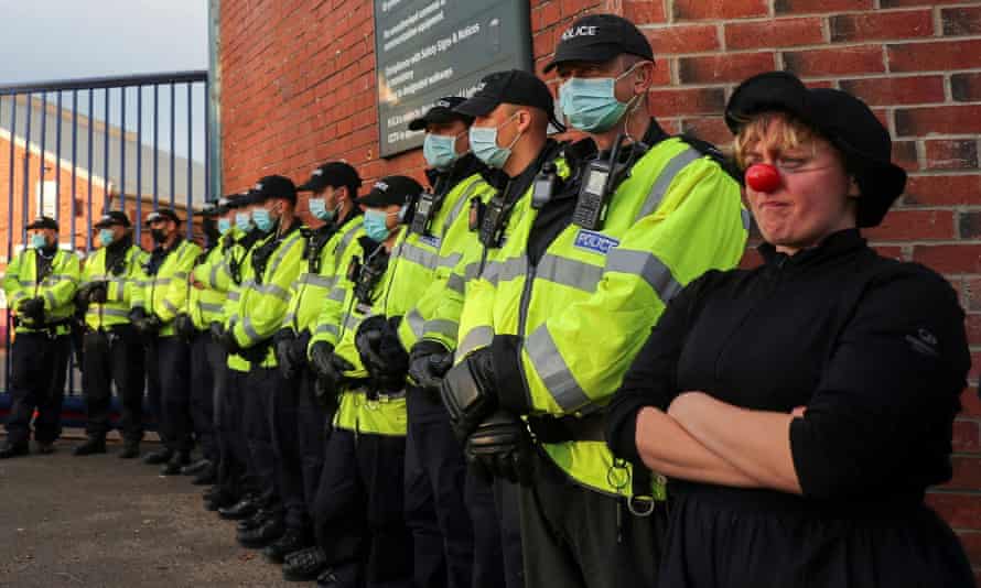 An Extinction Rebellion activist wearing a clown's nose stands next to police officers during a protest at Cop26 summit