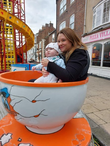 Rebecca Anderson sits in a giant cup on a fair ride with her son
