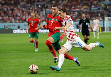 Croatia's Luka Modric surges past Morocco's Hakim Ziyech.