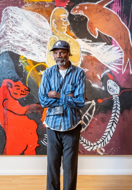 Fabian Brown, part of the ‘Tennant Creek Brio’ at Nyinkka Nyunyu Art &amp; Culture Centre, in front of his painting for Desert Mob 30, Sad Angel with his creatures, The Divine Dolphin, and The Red Hippo.