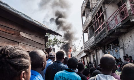Residents look on as smoke rises after the plane crash in Goma, Democratic Republic of Congo