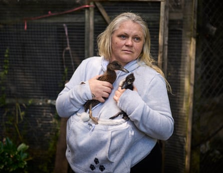 A woman outdoors holds two ducks