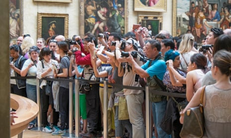 Tourists photographing the Mona Lisa at the Louvre in Paris
