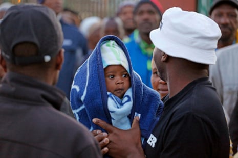 A man holds his baby in the township of Nyanga on the outskirts of Cape Town, South Africa