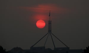 The sun sets through the he smoke haze over Parliament House Canberra