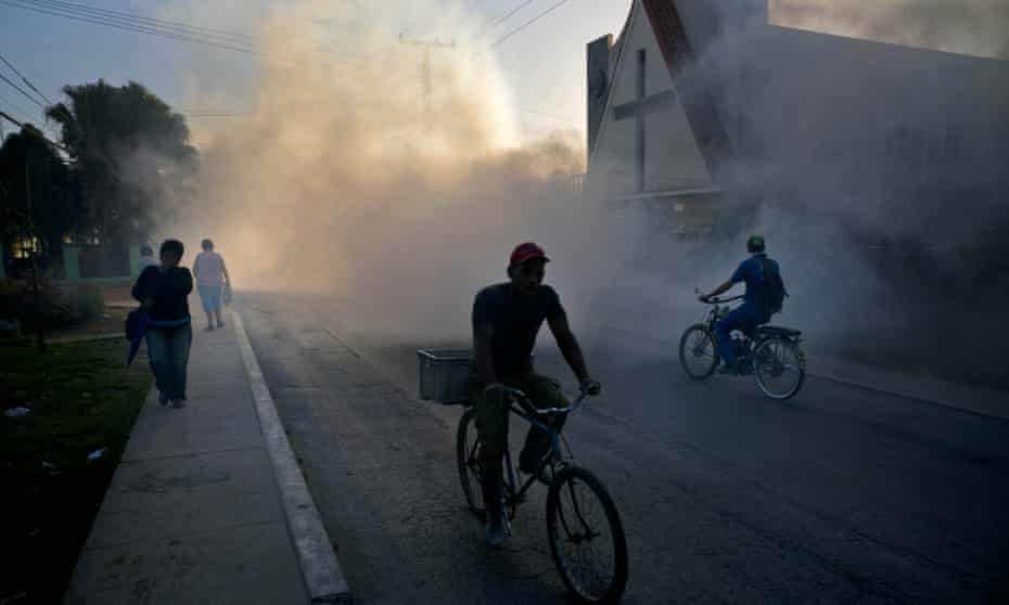 People make their way through fumigation fog, sprayed to kill mosquitos in Cuba.
