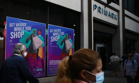 Pedestrians walk past a poster advertising in-store vaccinations at Primark on Oxford Street in London, England.