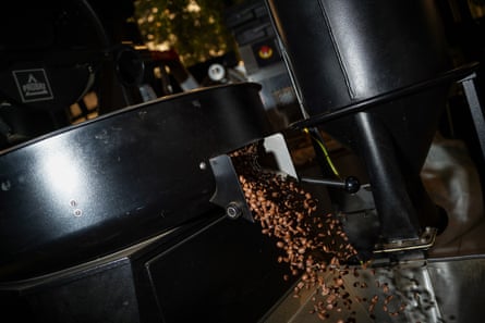 Roasted coffee beans pour out of a circular container at Café San Rafael