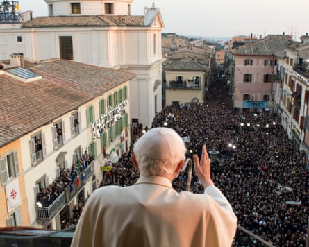 Pope Benedict XVI looking out from a high balcony over a crowd in a public square