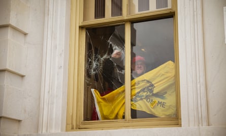 A member of a pro-Trump mob shatters a window inside the Capitol after breaking into the building.