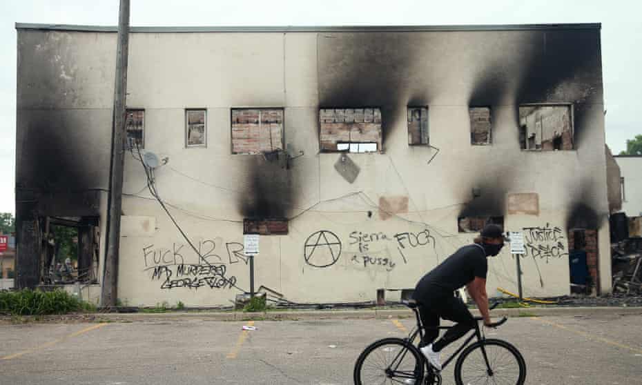 A man rides a bicycle past a burned out building Friday after a night of protests and violence in Minneapolis, Minnesota. 