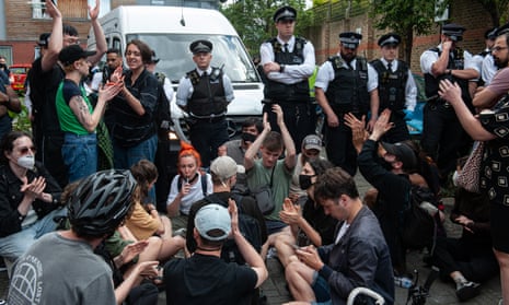 Protesters surround police officers standing beside a van