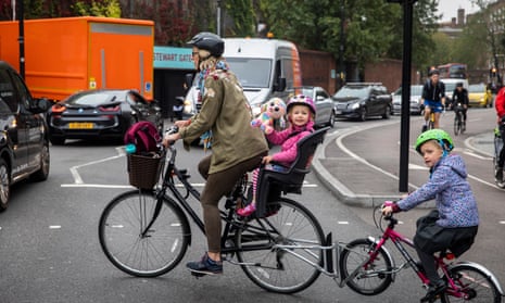 Family cycling to school in rush hour. Children suffer from high levels of pollution on London’s roads.