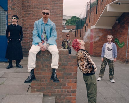 The band all standing around buildings and an outdoor staircase