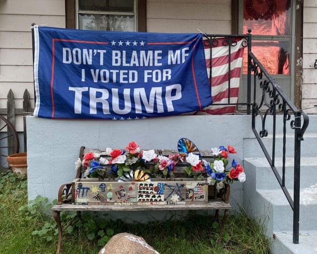 A blue flag hangs from the porch railing of a home in Wisconsin. Written on the flag is 'Don't blame me, I voted for Trump'.